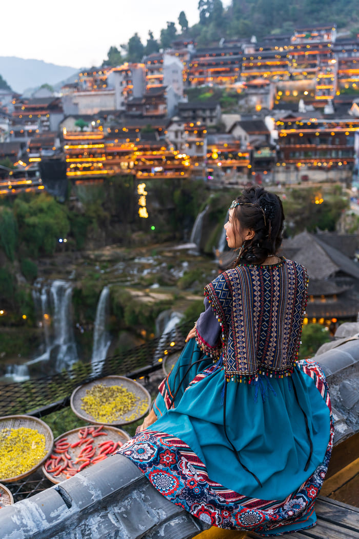 Una mujer sentada observando la ciudad de lijiang china